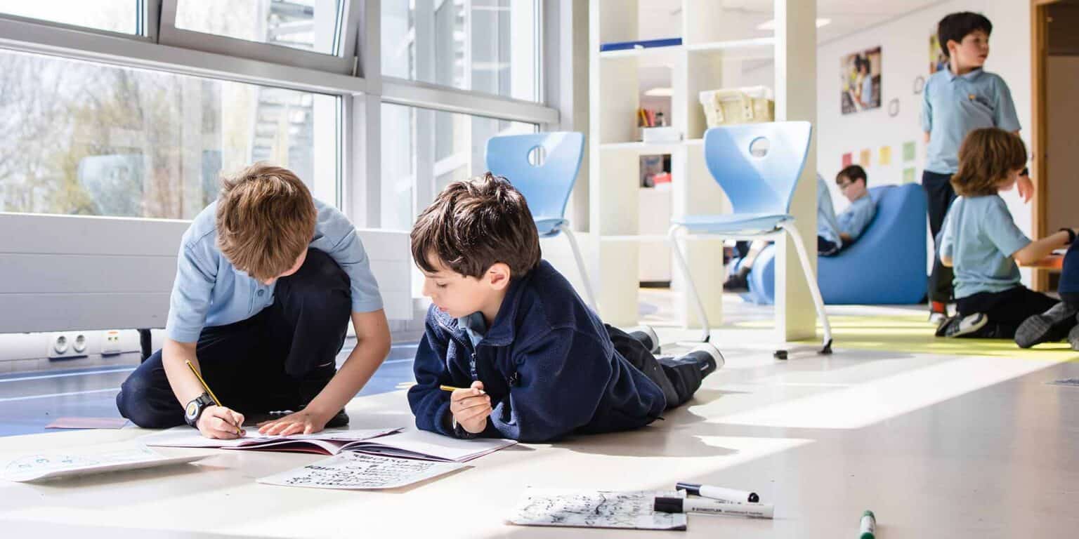 在世界学校的现代化教室里,聪明的小学生们正在合作完成一个学校项目。.