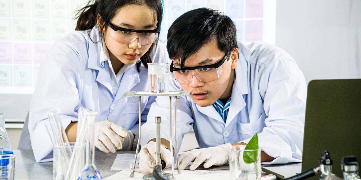 Students conducting science experiment in a classroom, focusing on chemistry, innovation, and education.