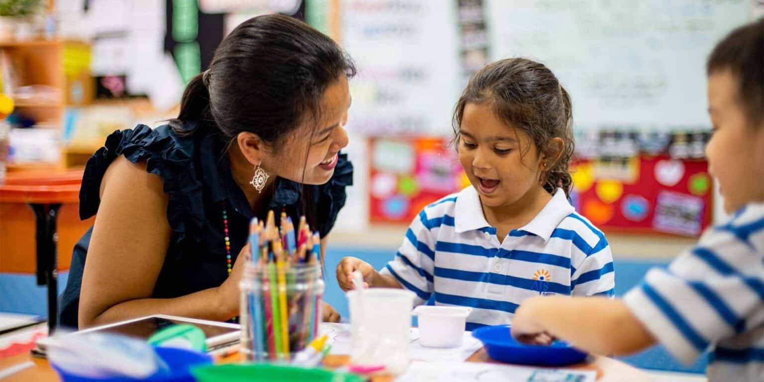 Engaged teacher guiding young students in a colorful classroom for personalized learning.
