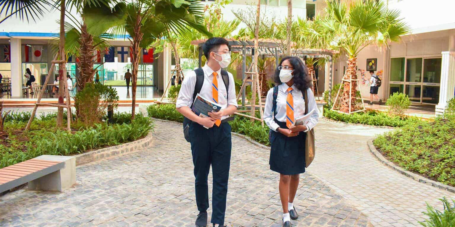 Modern international school campus with students in uniforms, lush greenery, and a vibrant educational environment.