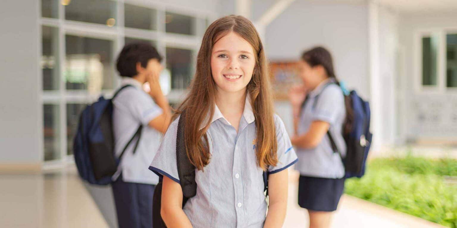 Bright young girl smiling at camera, happy students at World Schools, diverse education community image.