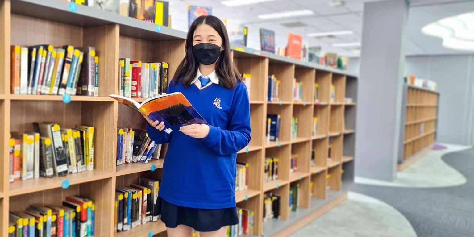 Young girl studying in library at a world schools' educational institution.