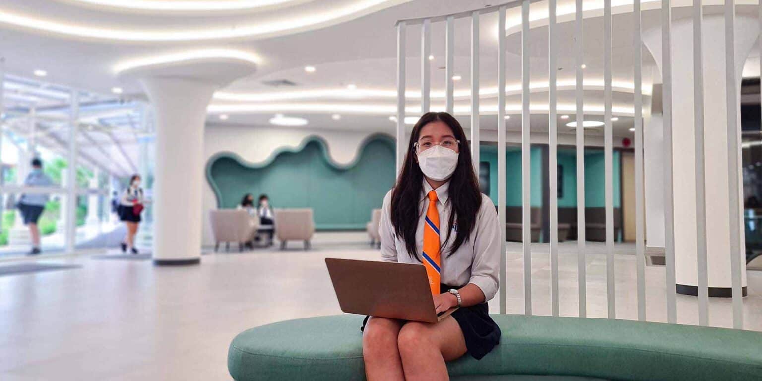 Modern school lobby with students, bright lighting, and contemporary design emphasizing global education.