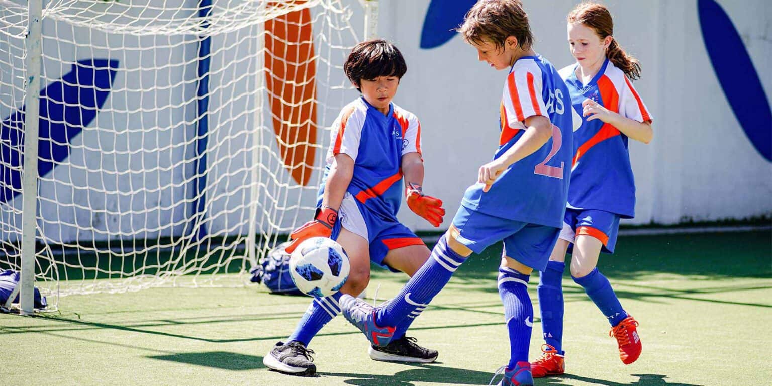Young children playing soccer on a vibrant outdoor sports field, fostering teamwork and physical activity.