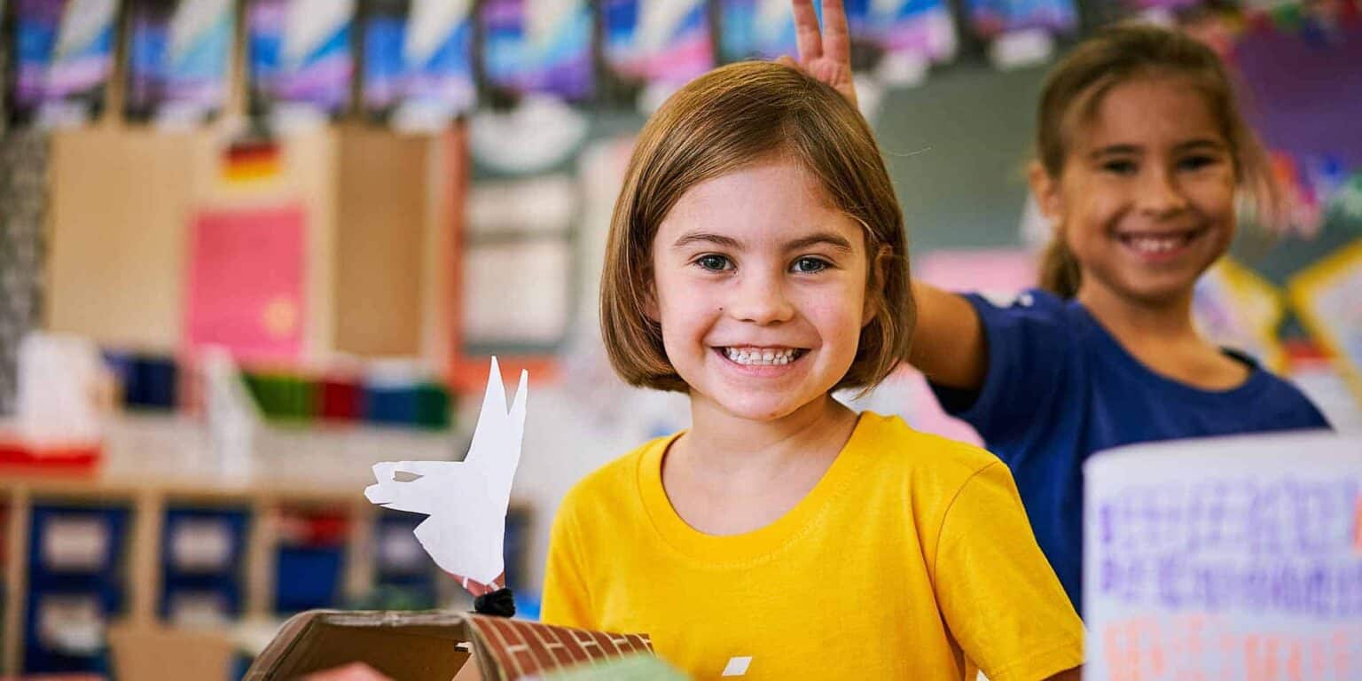 Bright smiling schoolgirls engaging in classroom activities at an international school.