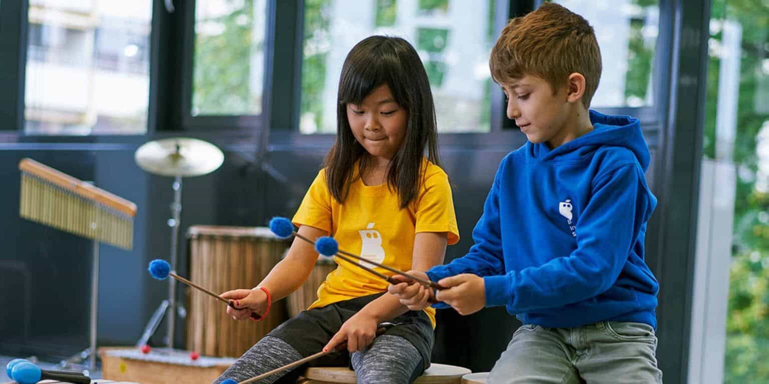 Colorful school uniforms on young students engaging in music therapy in a bright classroom.