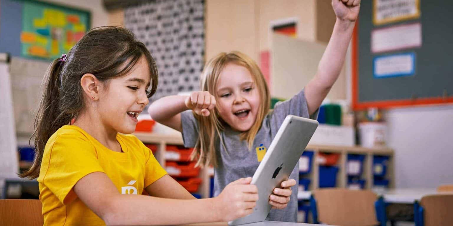 Friendly young girls exploring educational technology in a lively classroom, promoting innovative learning at World Schools.