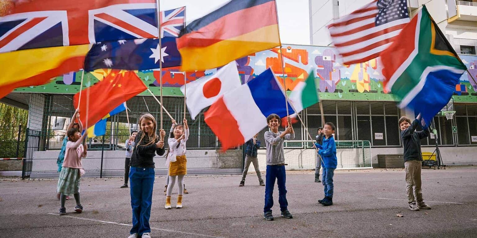 Colorful international flags flying at a diverse school campus.