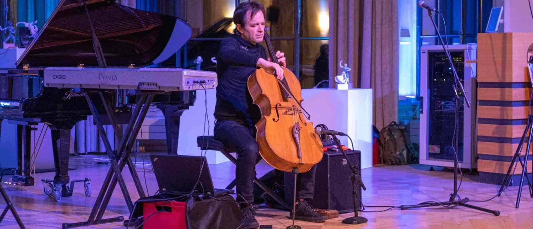 Elegant musician playing cello at a music event in a modern studio setting.