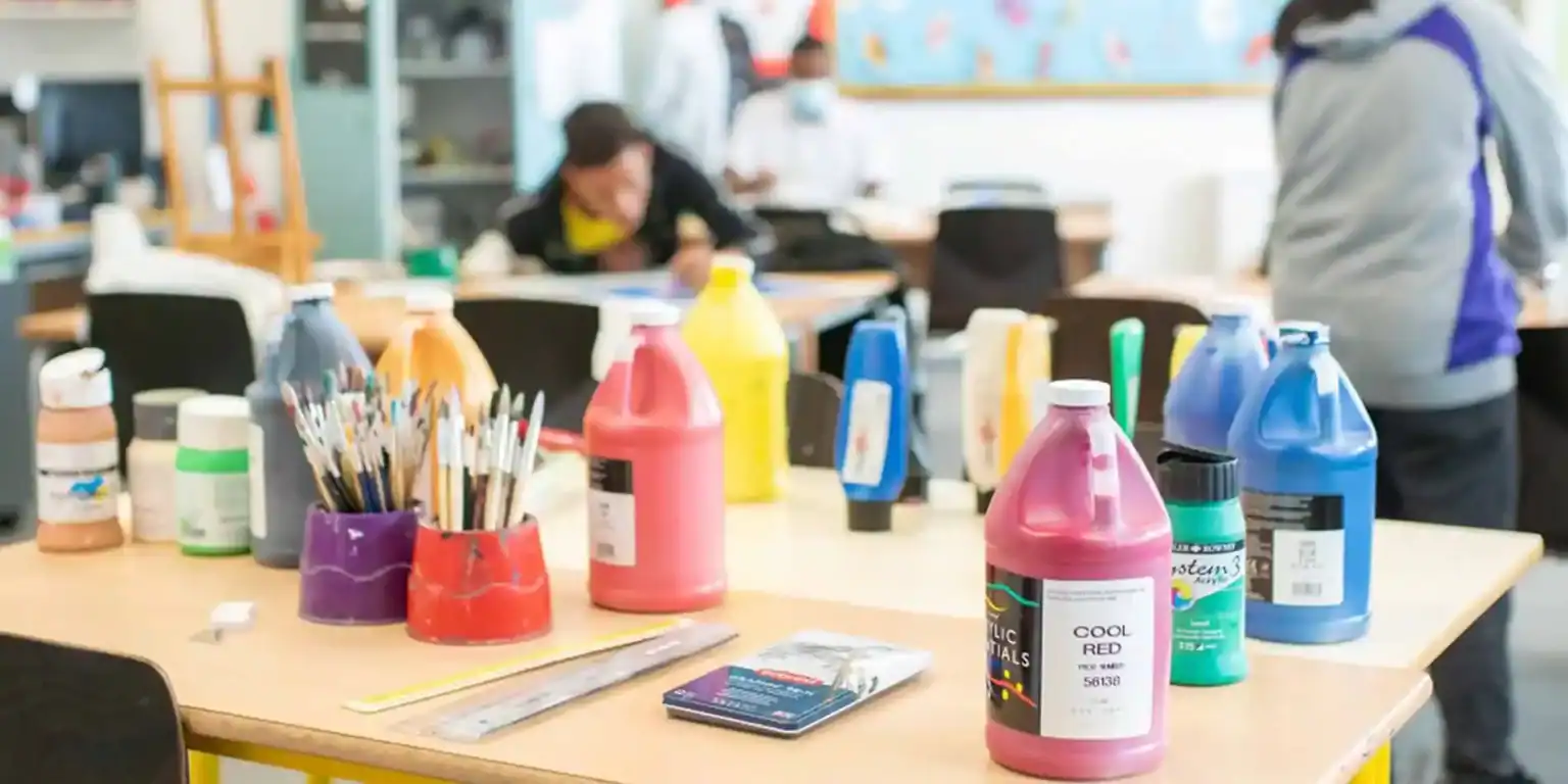 Colorful paint bottles and art supplies in a vibrant classroom at a prestigious world school.