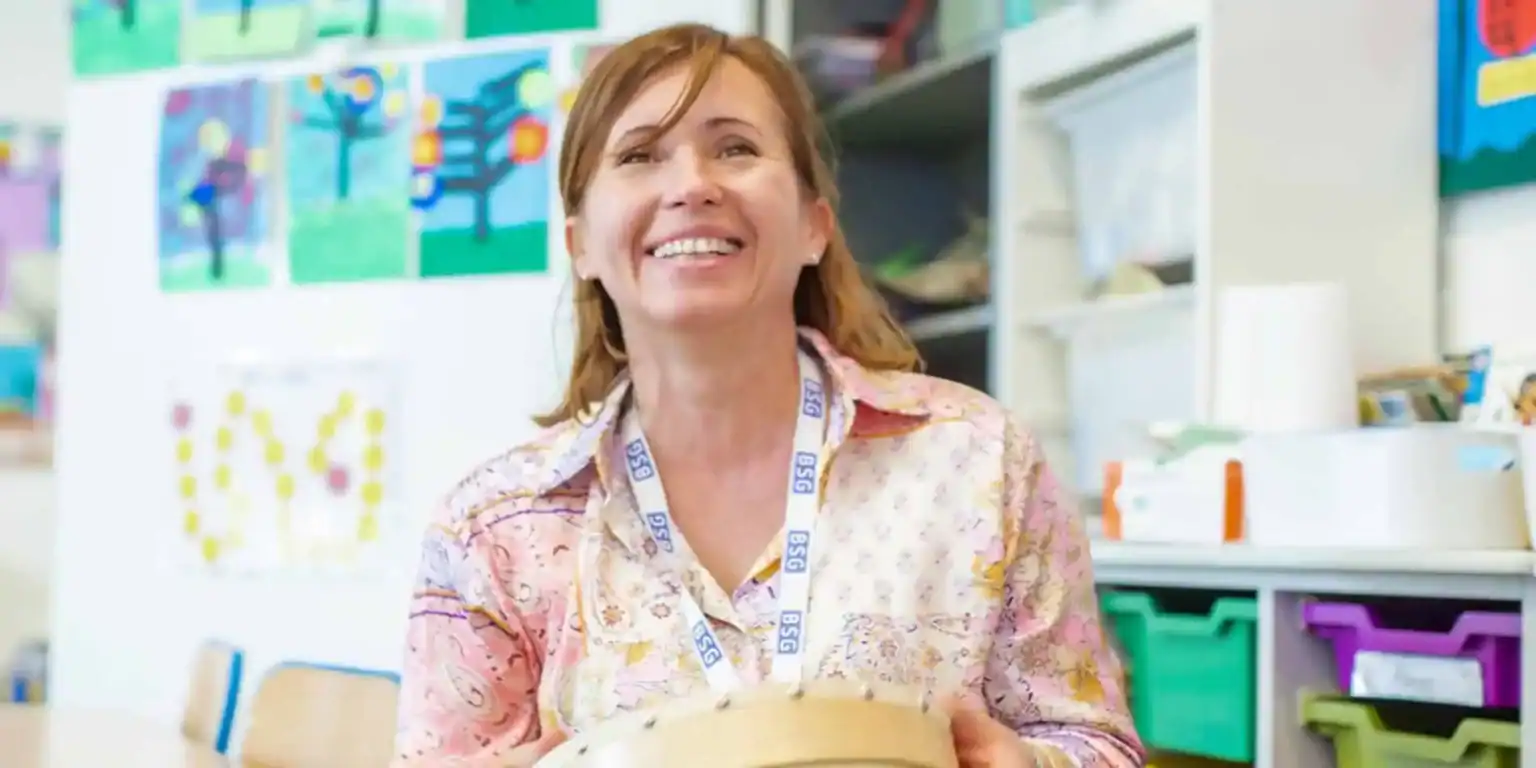 Engaging teacher smiles in a vibrant classroom environment with colorful wall art and educational supplies for optimal learning.
