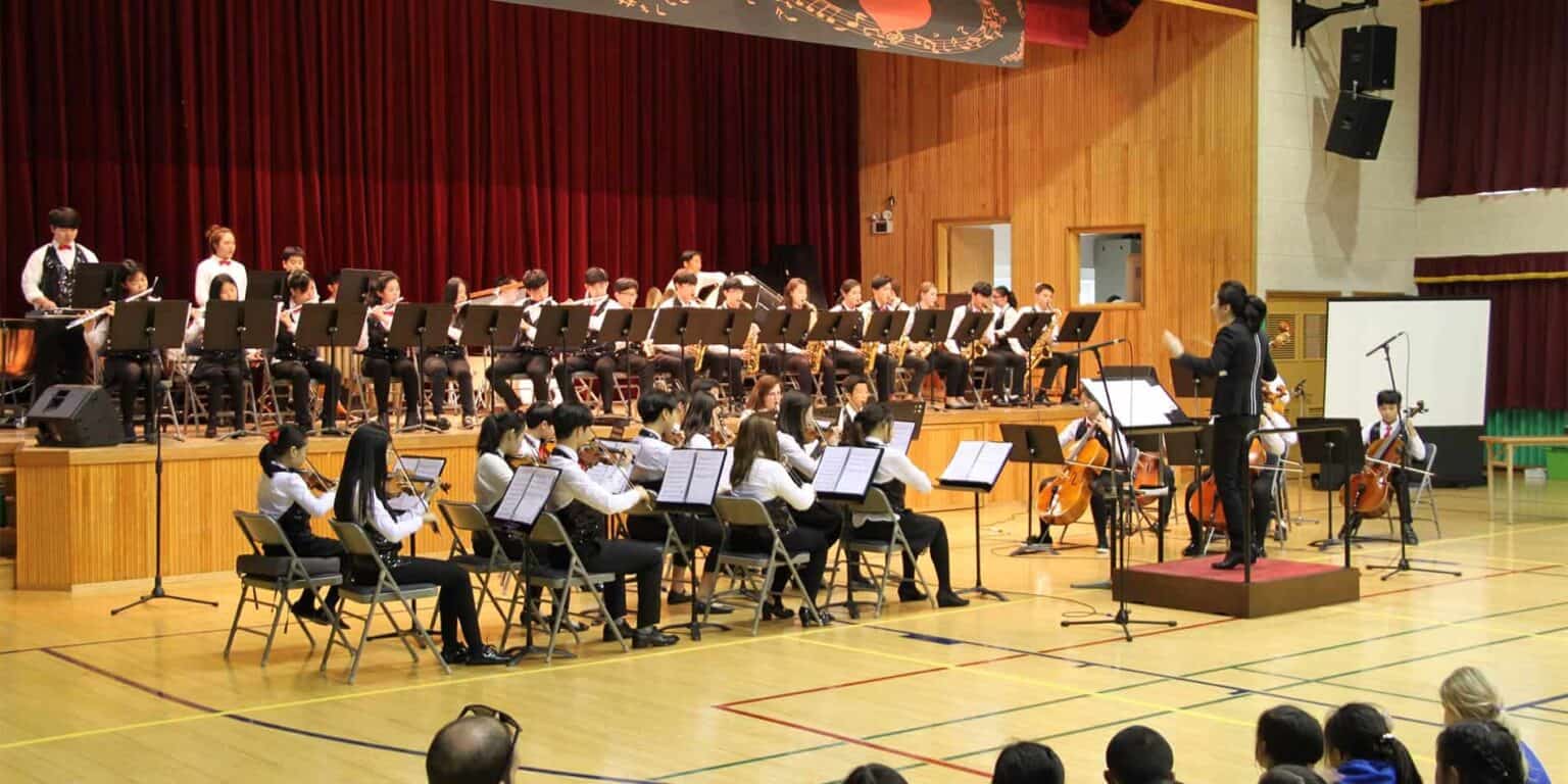 Orchestra performance by students at a school auditorium, demonstrating excellent music education and arts program.