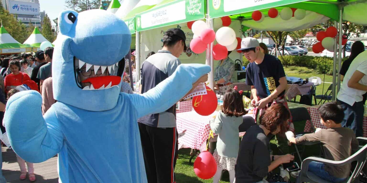 Friendly mascot at outdoor school event promoting global education and cultural exchange.