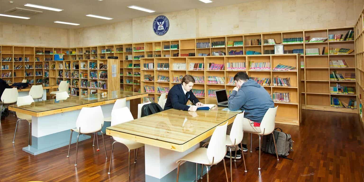 Quiet library with students studying and reading books at wooden tables, educational environment, perfect for learning.