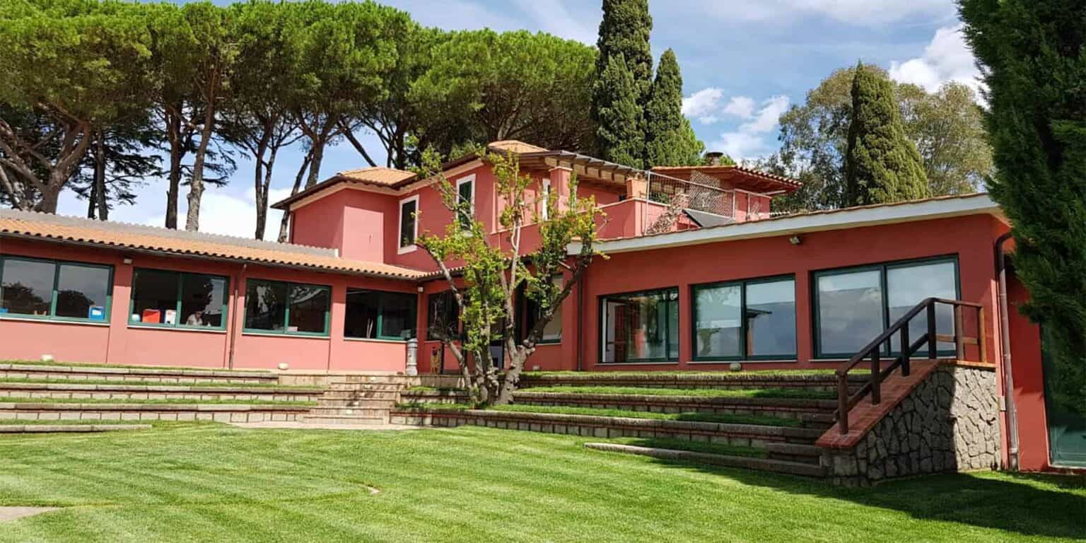 Modern international school building with large windows and lush green surroundings, ideal for global education.