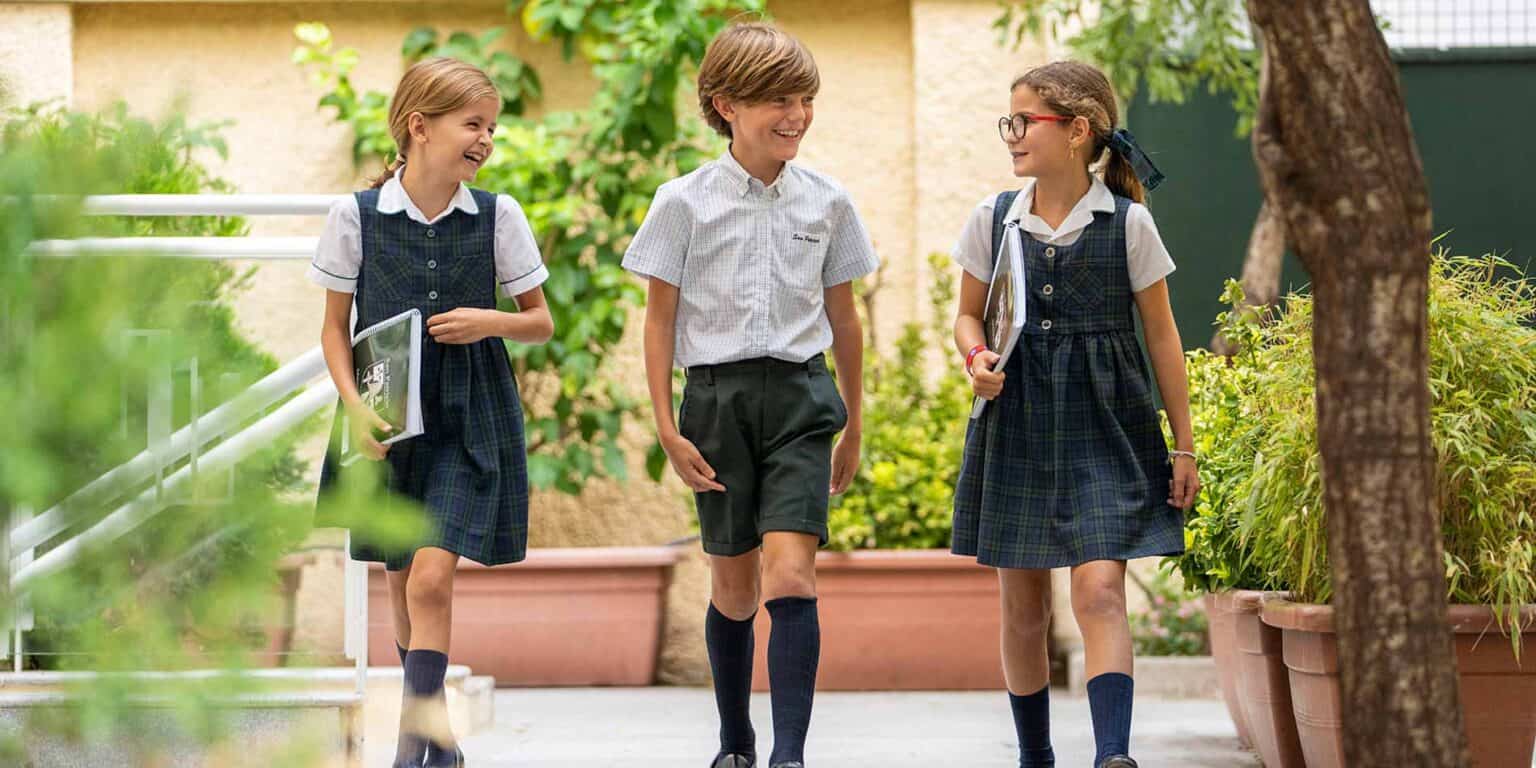 Focused on international education, students in school uniforms walk and chat outside at a global school.