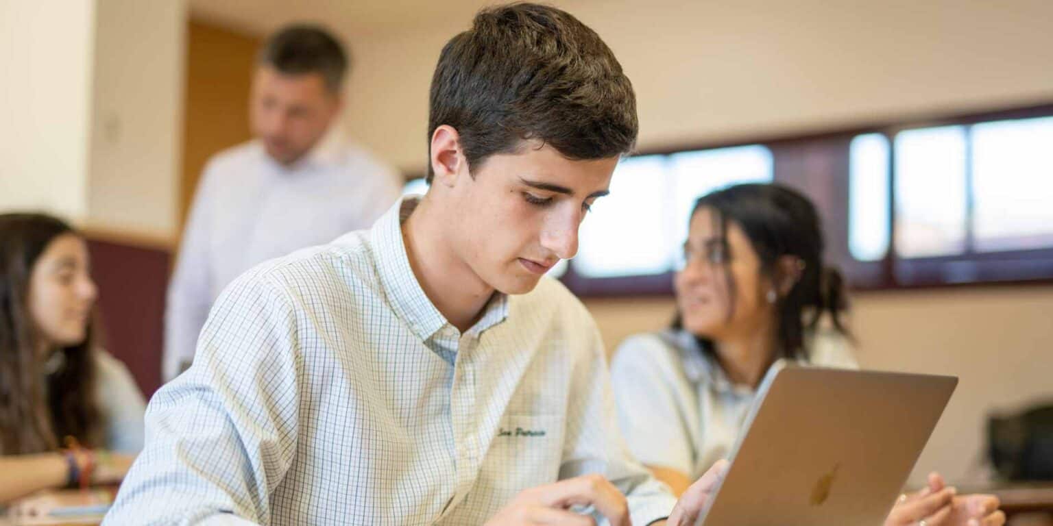 Engaged student using a laptop during class at a World Schools educational institution.