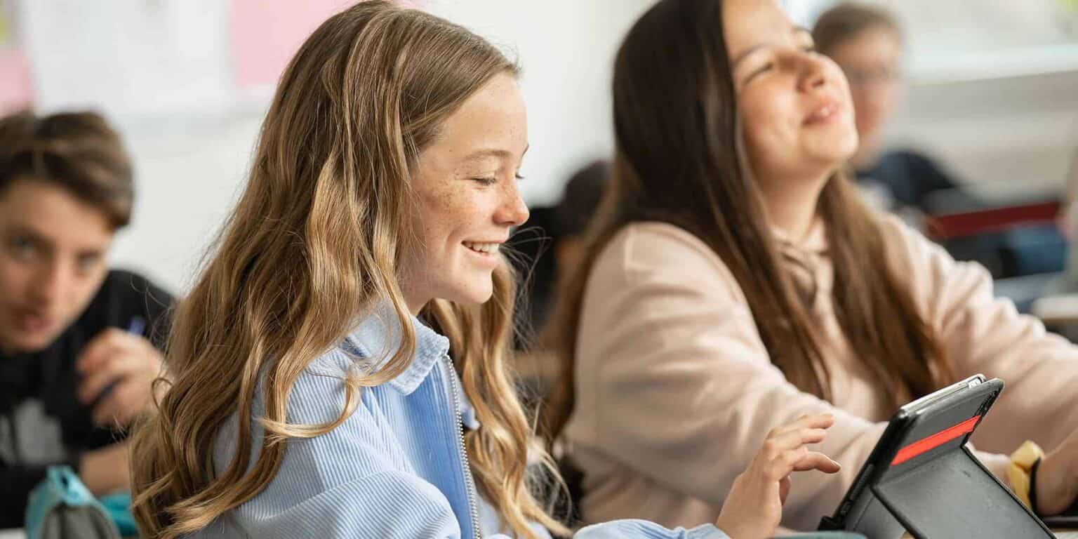 Bright, happy students engaging with tablets in a modern classroom at a world school.