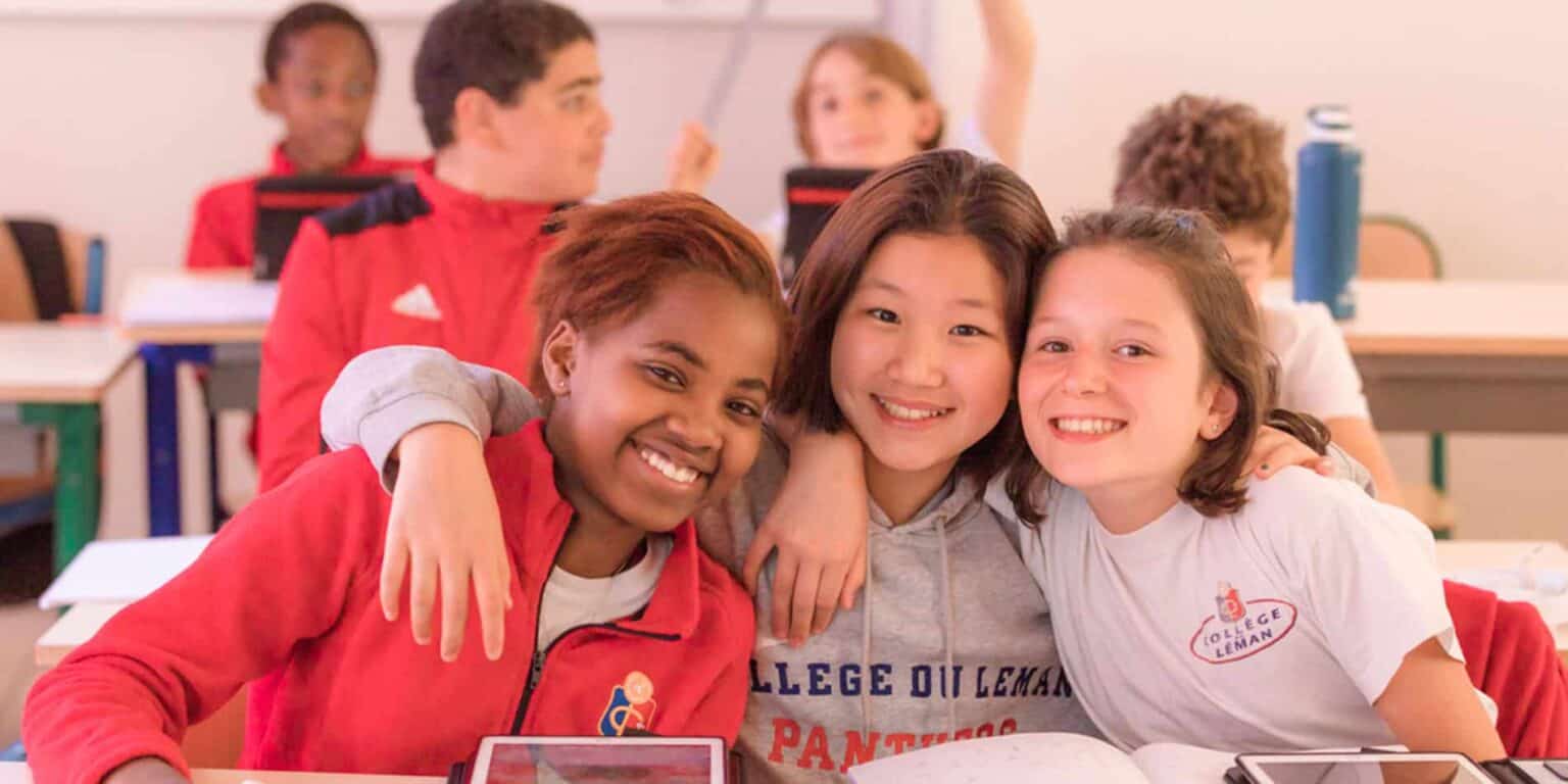 Diverse joyful students smiling in classroom at World Schools, creating a positive learning environment.