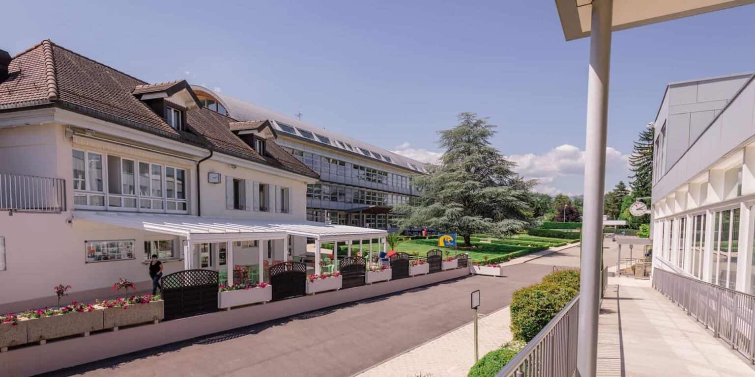 Modern international school campus with lush greenery and outdoor play areas for students.