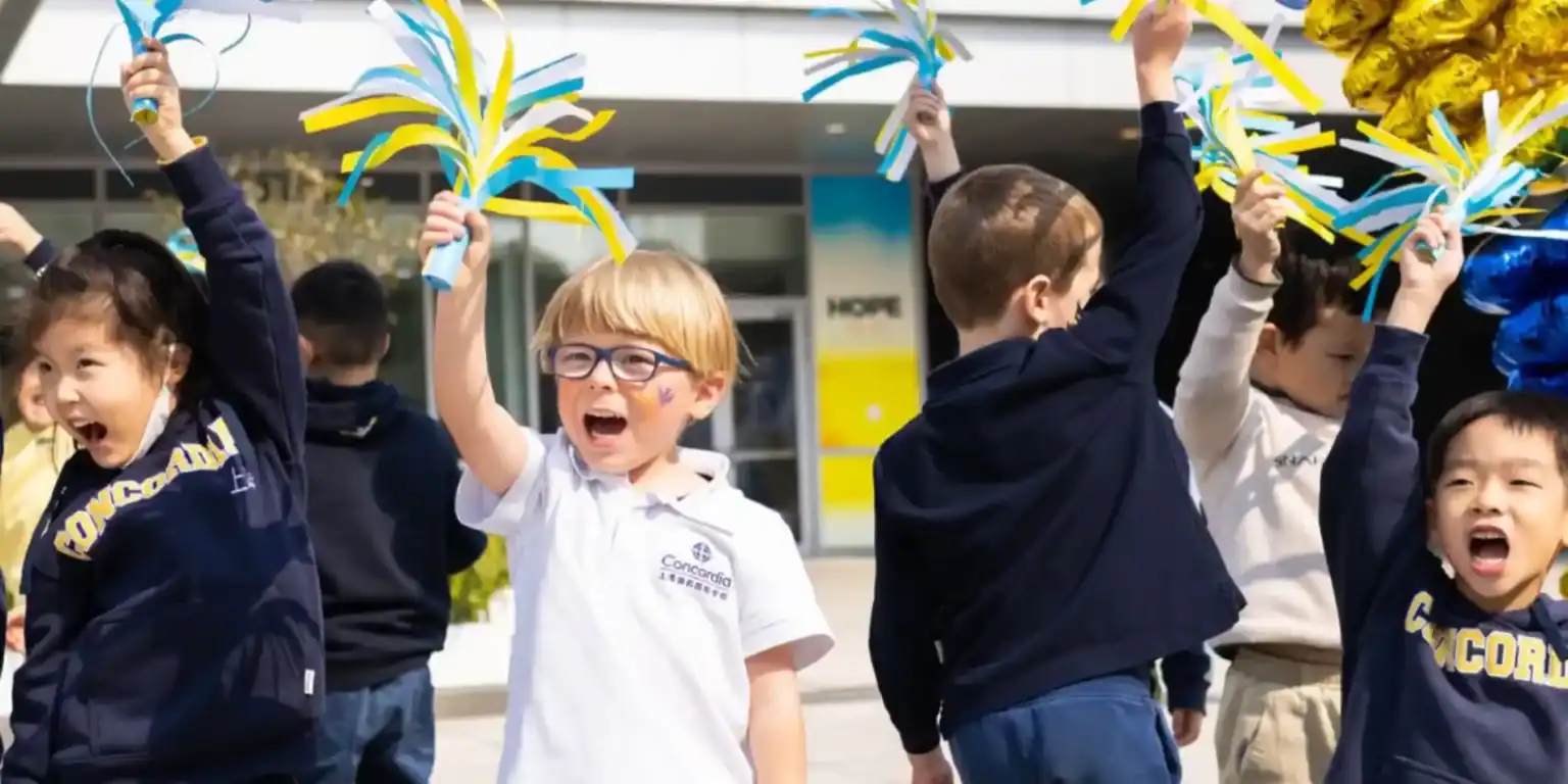 Bright young students celebrating outdoors at Concordia International School with colorful ribbon toys.