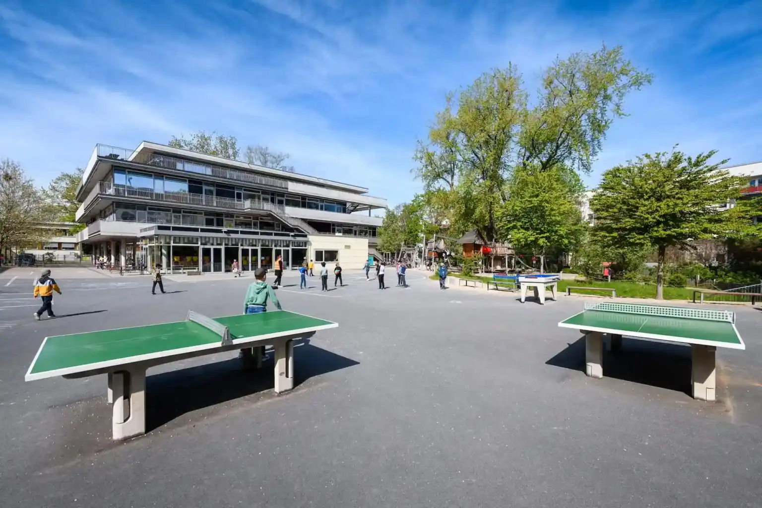 Bright outdoor playground and school building at a top World School with ping pong tables and green spaces.
