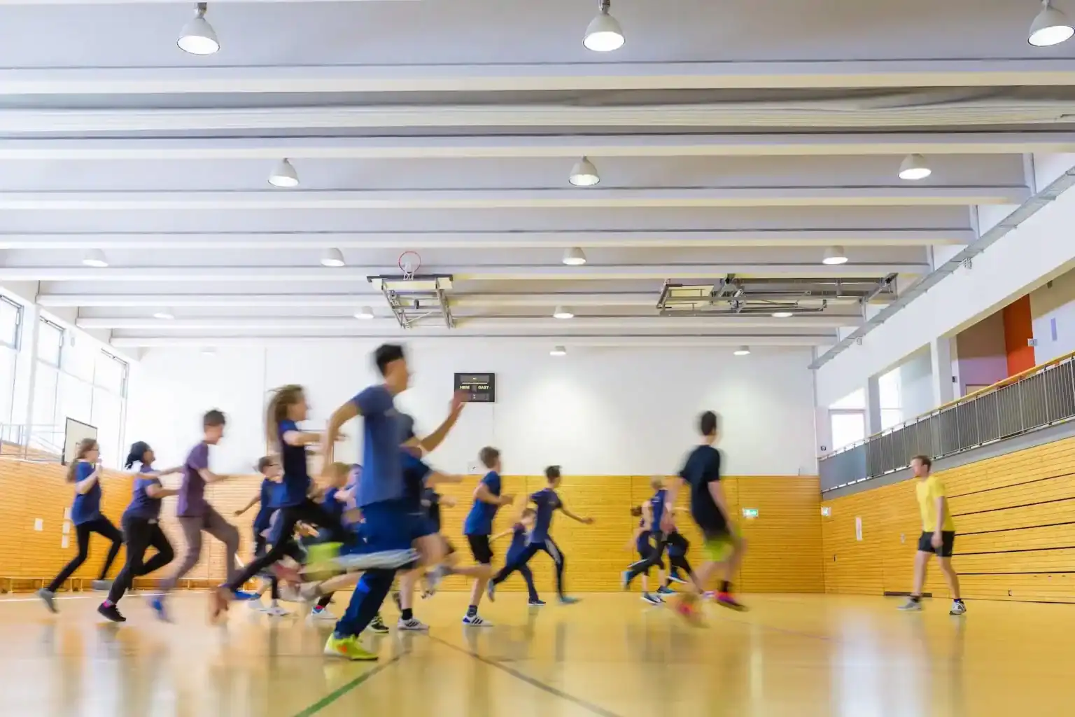 Active children playing basketball in a school gymnasium, promoting student sports and health.