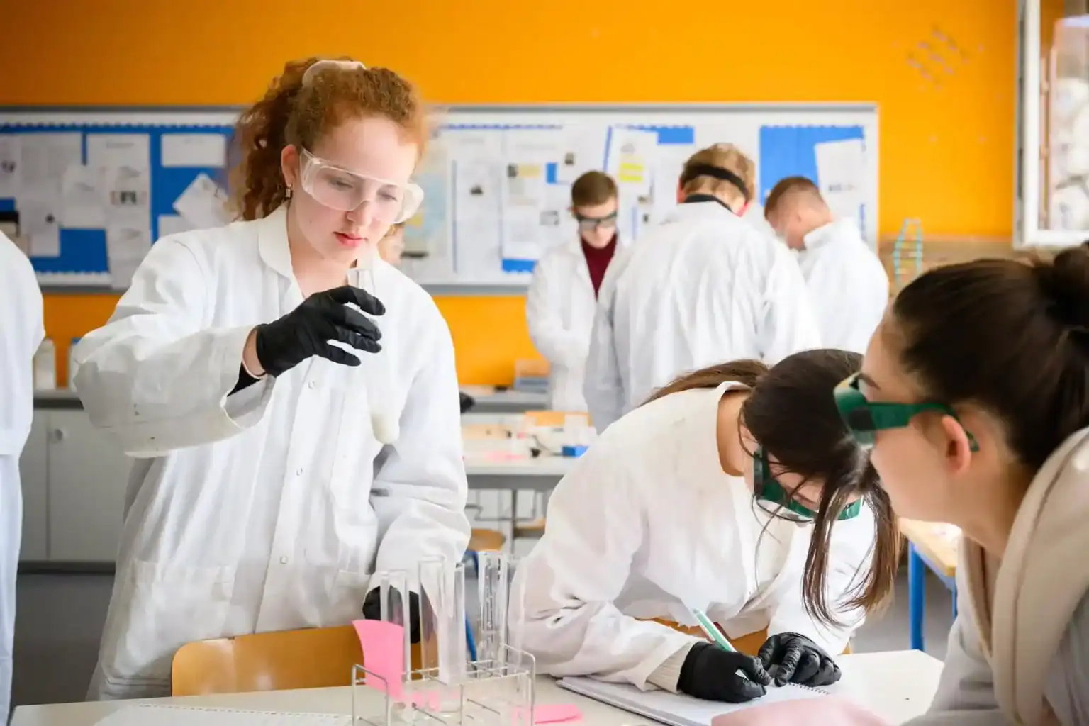 Young students conducting science experiments in a classroom, wearing lab coats and safety goggles for practical learning.