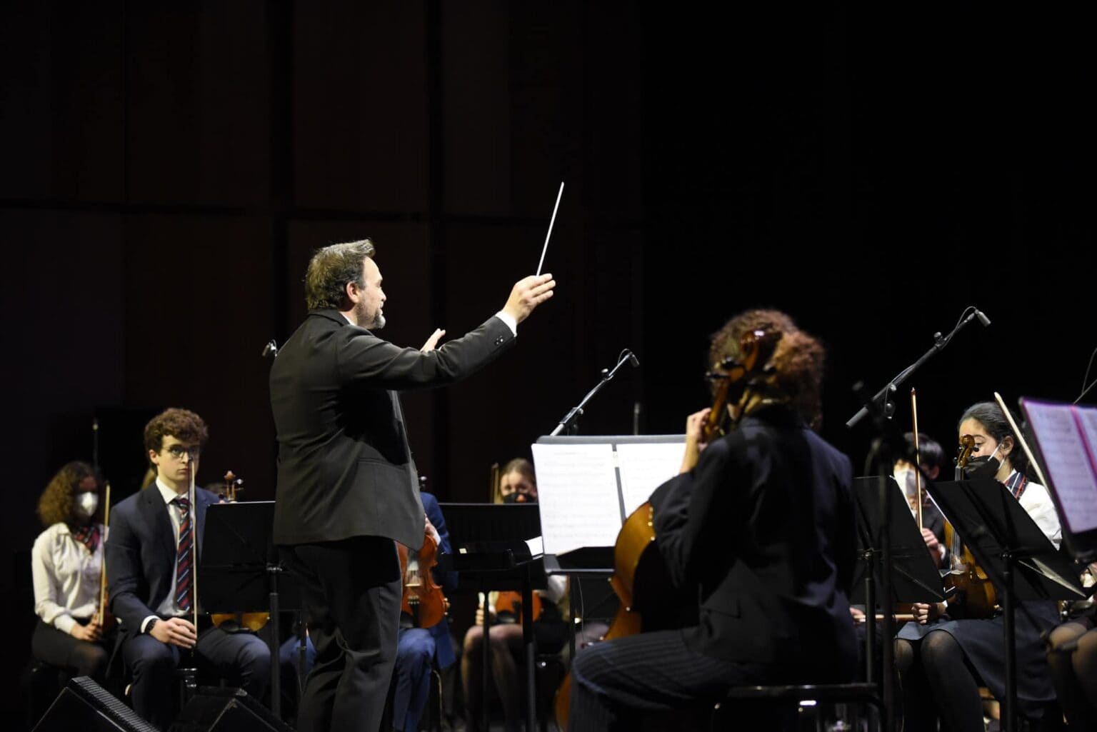 Esibizione di direzione d'orchestra in occasione di un evento scolastico mondiale, che mette in luce la diversità culturale e l'eccellenza musicale.