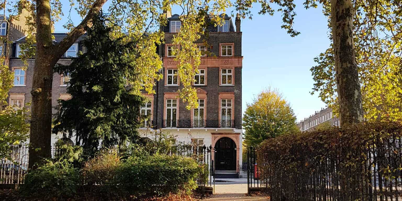 Edificio escolar de estilo histórico entre árboles otoñales, que promueve la excelencia educativa global.