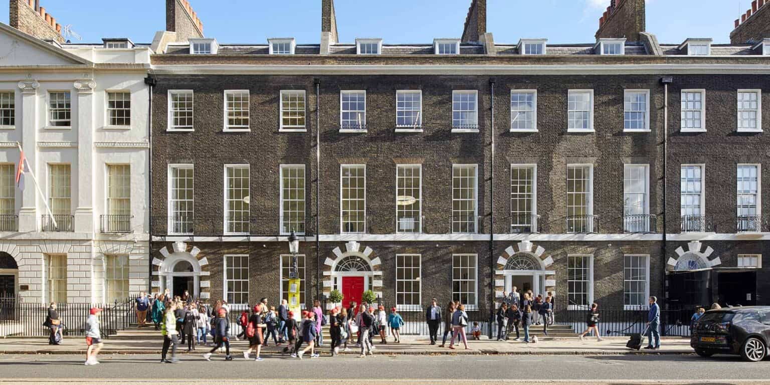 Modern historic school building with students and visitors outside, embodies international education excellence.