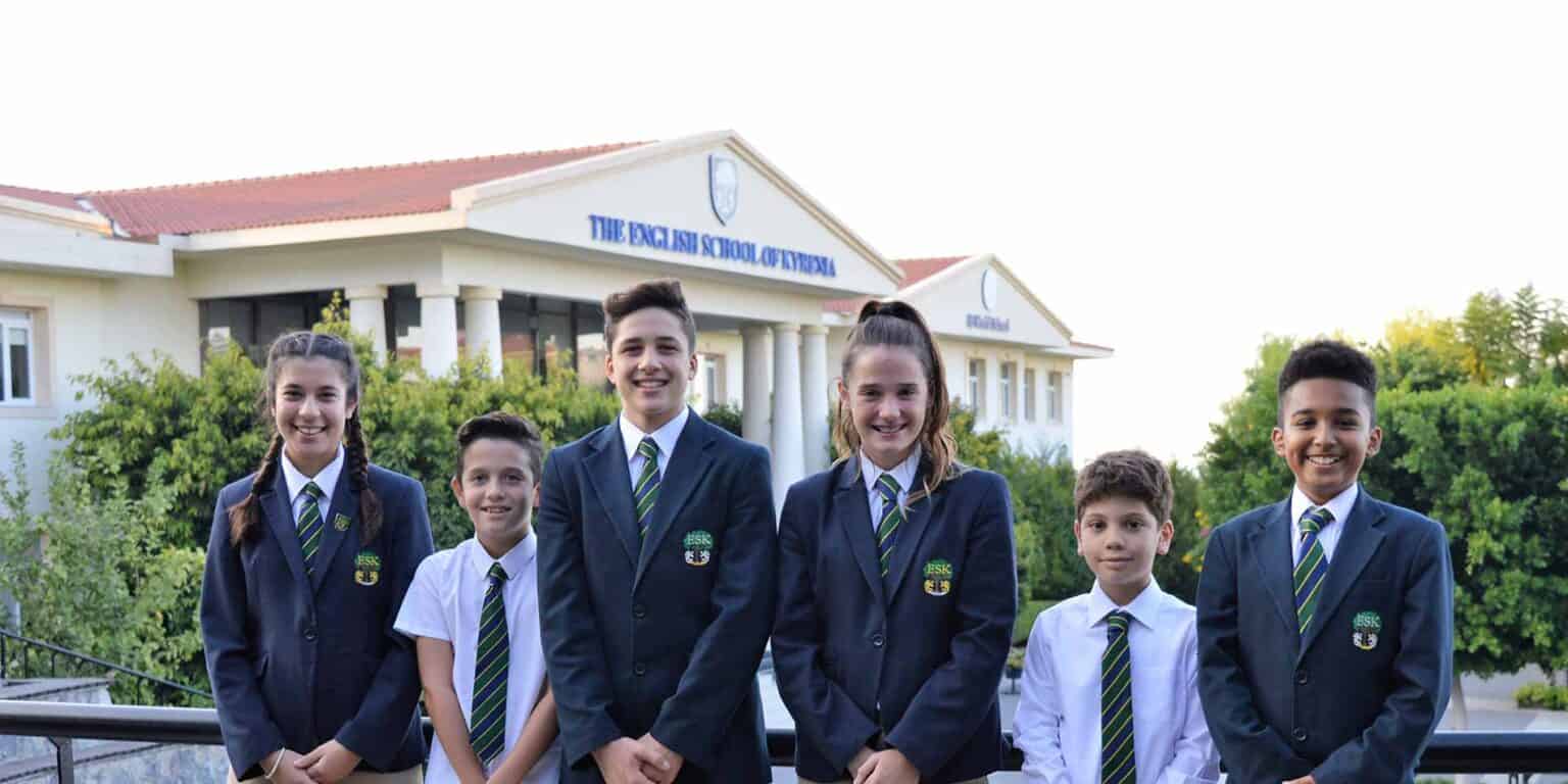 Bystrzy uczniowie w mundurkach stojący przed The English School of Yerevan, najlepszą międzynarodową szkołą o dobrej reputacji akademickiej.