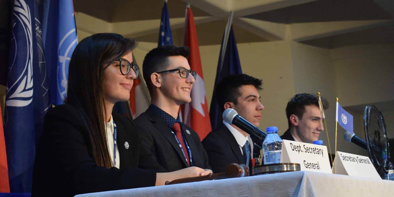 High school students participating in an international conference representing diverse countries, emphasizing leadership and global education.
