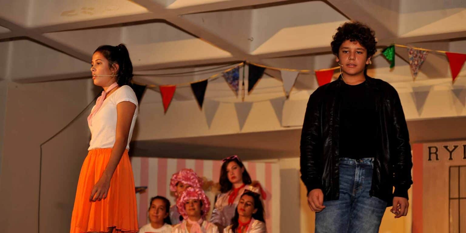 Colorful school performance with diverse students on stage for World Schools education.