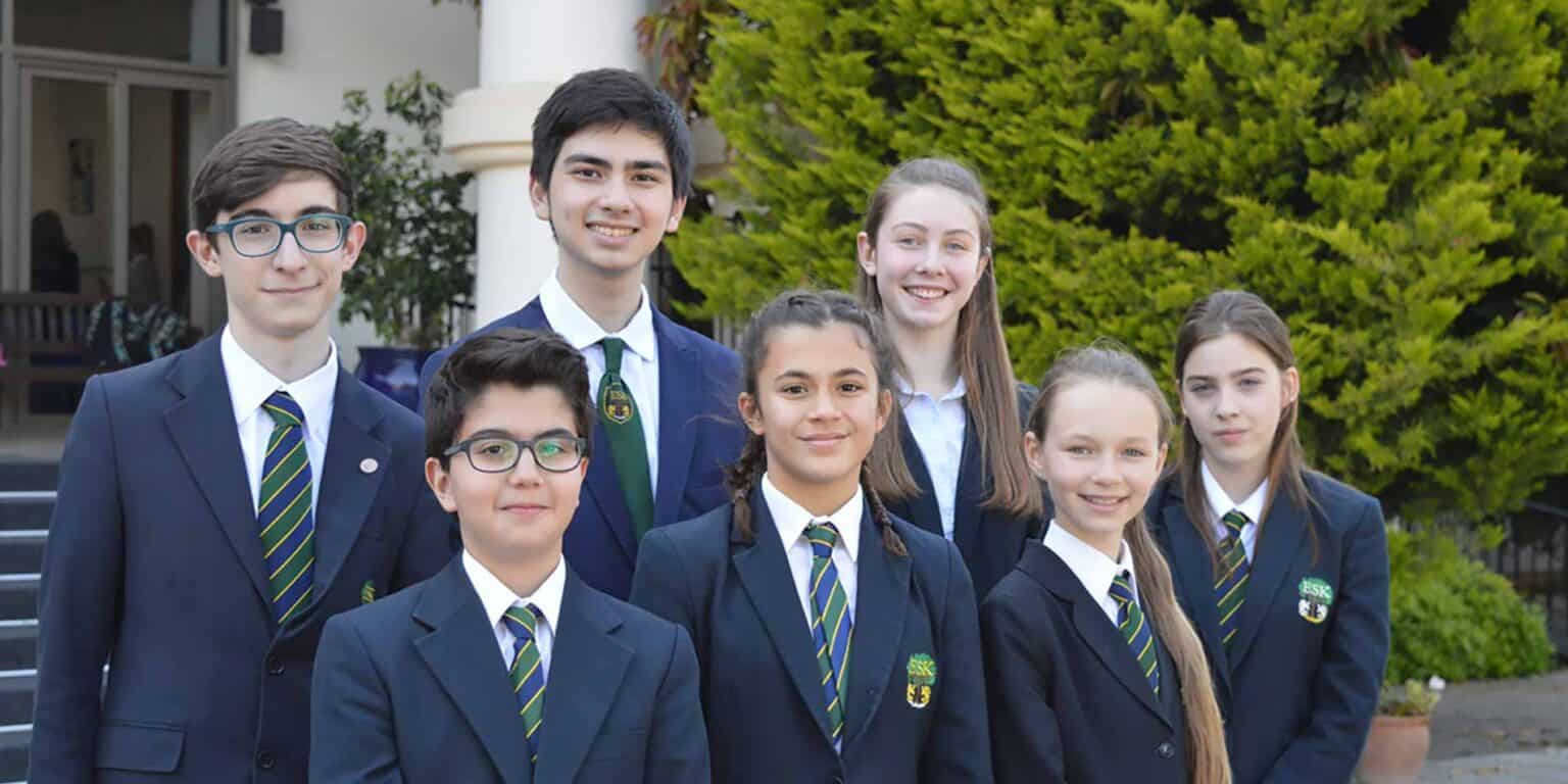 Diverse group of students in school uniforms smiling outdoors at World Schools campus for optimal education and global learning.