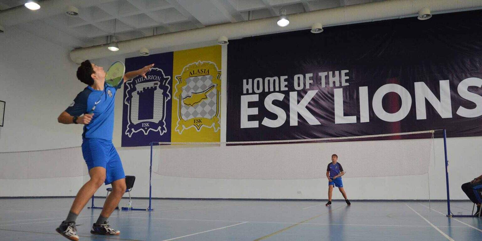 Young male student playing badminton in indoor sports facility at World Schools.