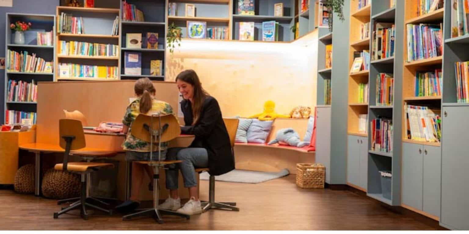 Bright school library with children and teacher, educational environment for learning and reading.