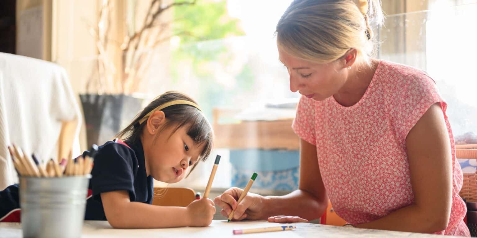 Child learning with teacher in a classroom, focused on global education and international school standards.