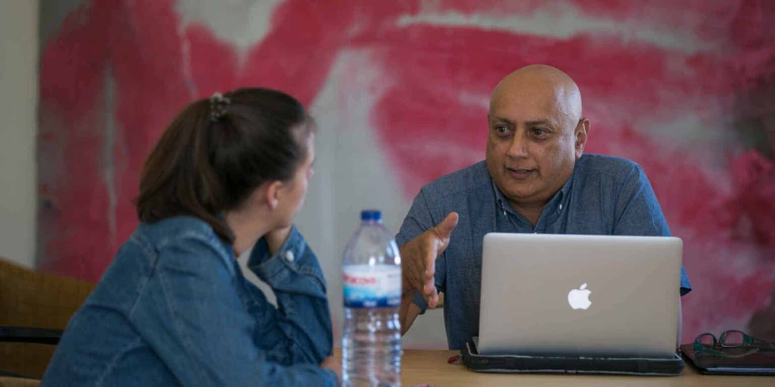 Engaging student-teacher discussion at World Schools with laptops for modern education.