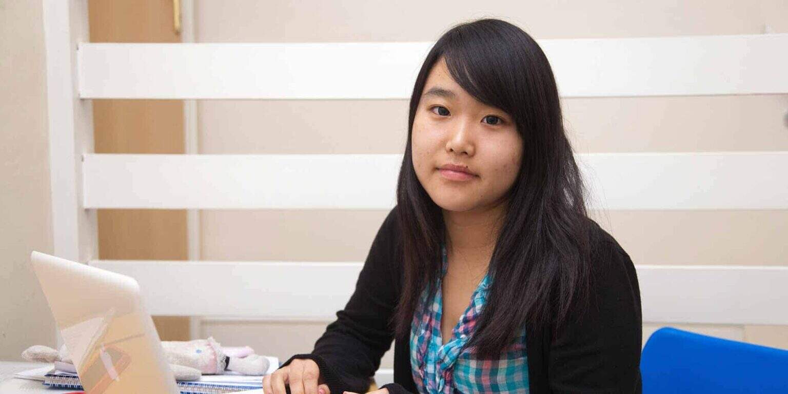 Diverse student studying at a desk in a modern classroom for global education excellence.