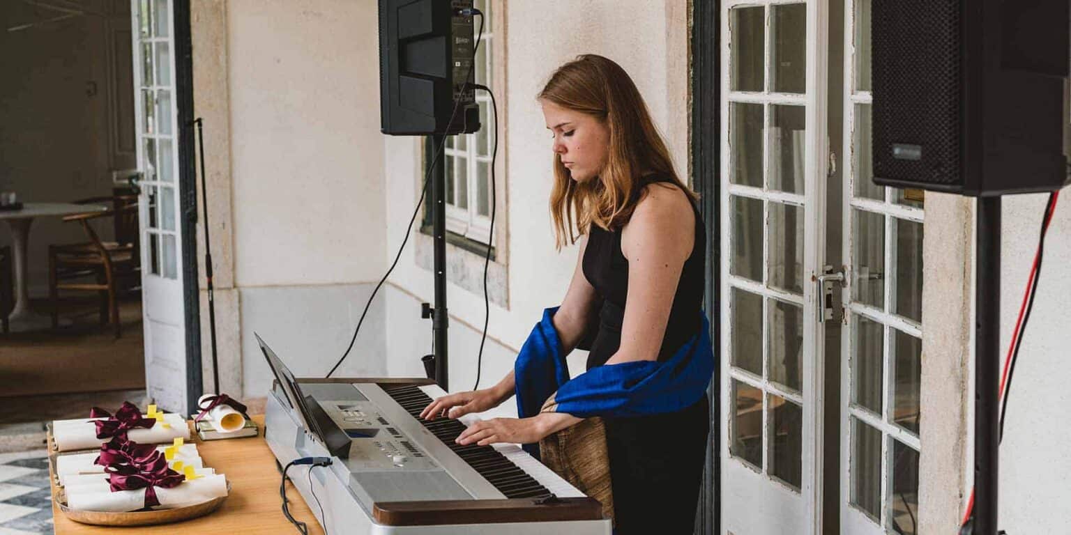Young woman playing keyboard at an indoor event, stylish tone, focused musician, live performance, privacy.