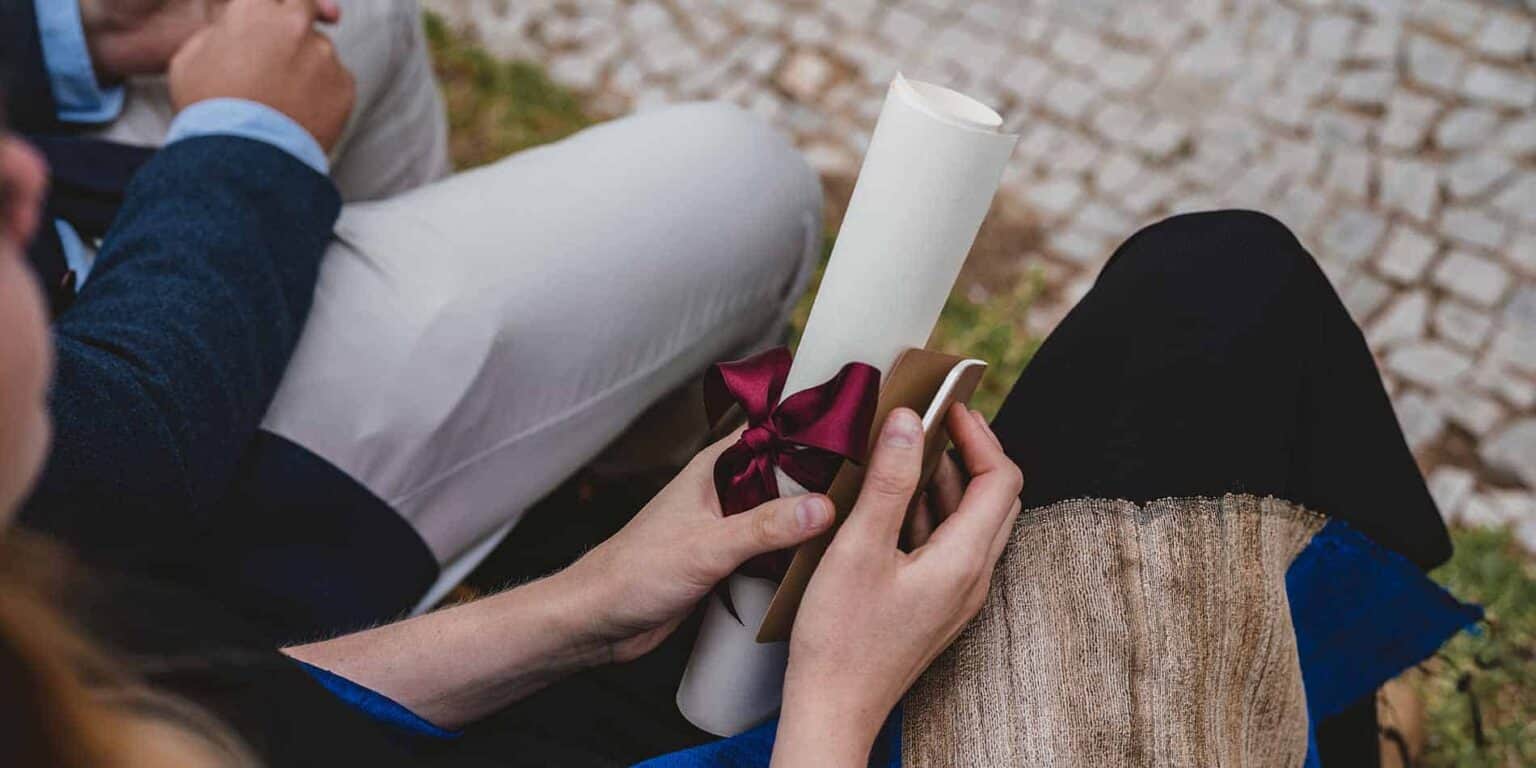 Elegant student holding a diploma certificate after graduation, celebrating academic success.