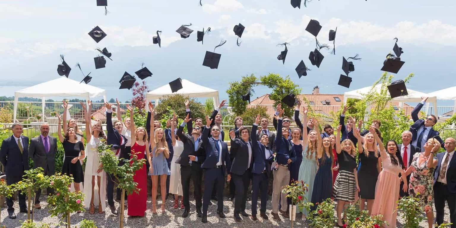 Graduates celebrate outdoor graduation ceremony with tossing caps and joyful expressions.
