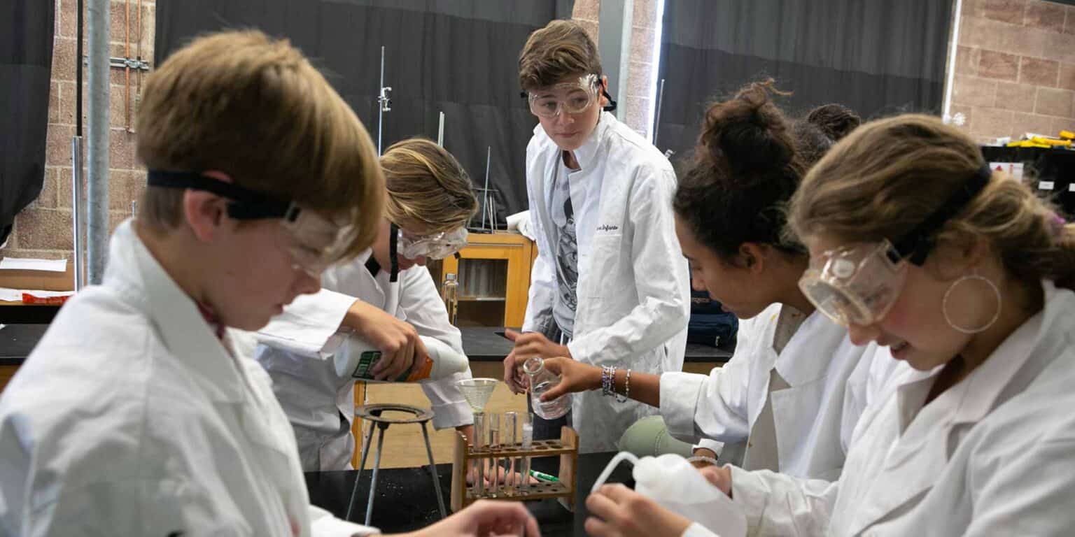 Bir okul laboratuvarında fen deneyleri yapan öğrenciler, uygulamalı öğrenme ve bilimsel keşifle meşgul olurlar.