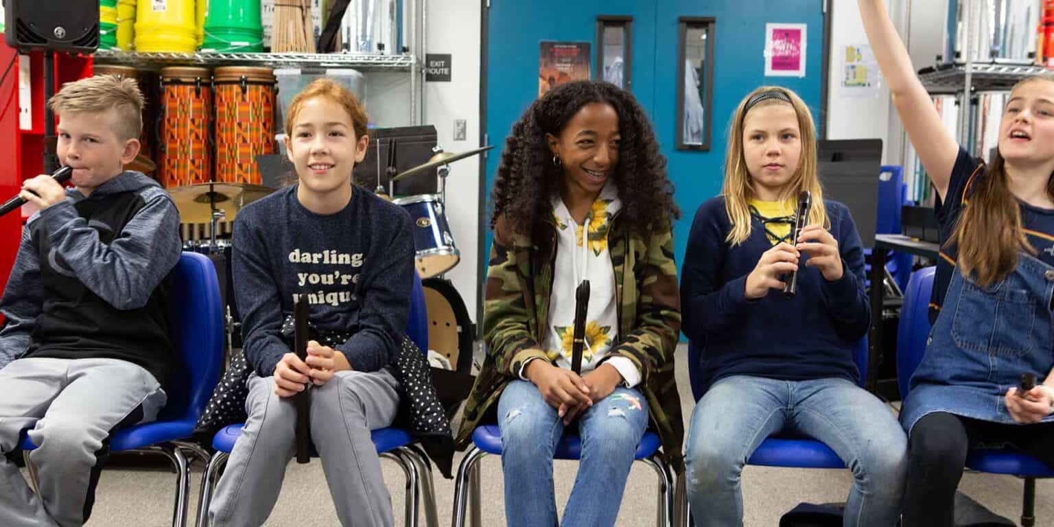 Children participating in a music class at a global school, showcasing diverse students involved in learning and creative activities.