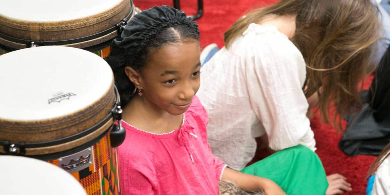 Vibrant classroom scene featuring young students engaging in musical activities with drums at World Schools.