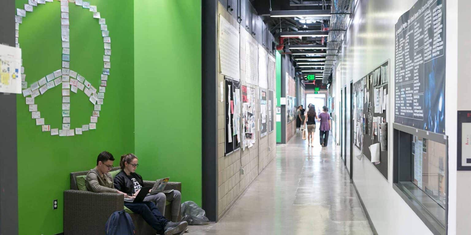 Bright school hallway with students and vibrant posters, showcasing a lively learning environment.