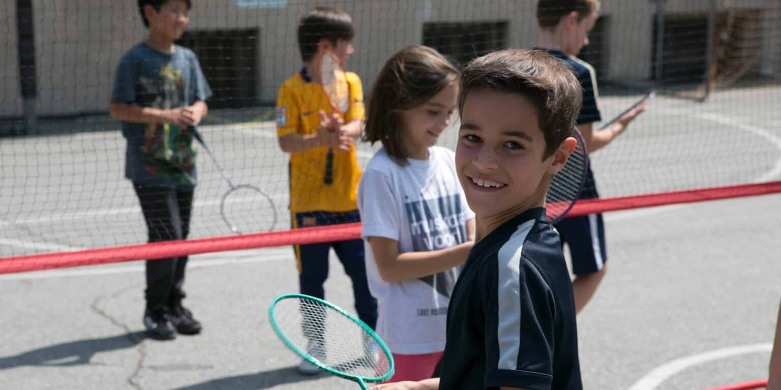 Bright young students enjoying tennis class outdoors at a world school.