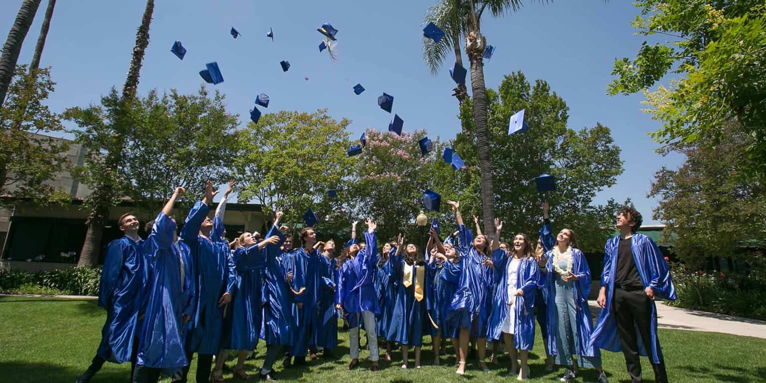 Graduates in blue gowns celebrating graduation day at a distinguished international school.