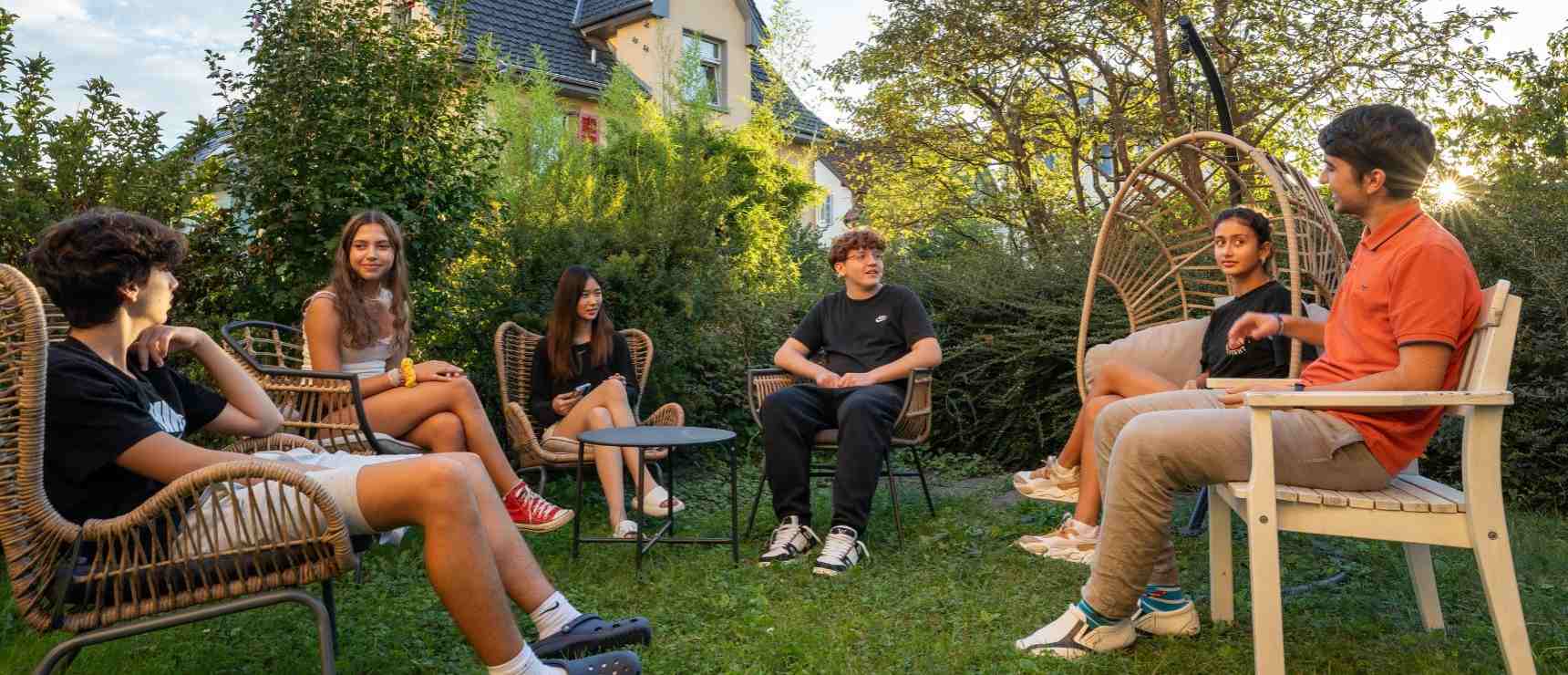 Diverse group of students engaging in outdoor discussion at an international school.